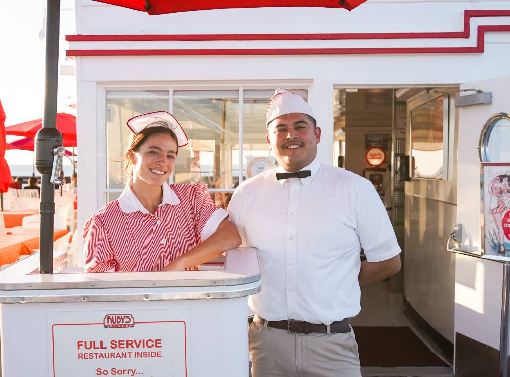 Two smiling team members standing outside a Ruby's location
