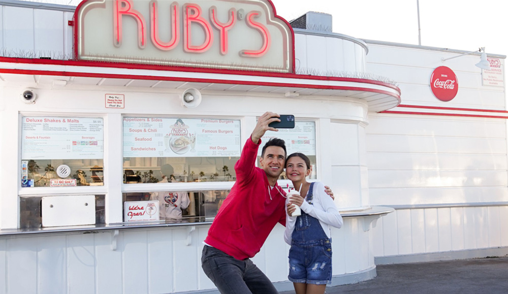 Father and daughter taking a selfie in front of Ruby's at Balboa Pier