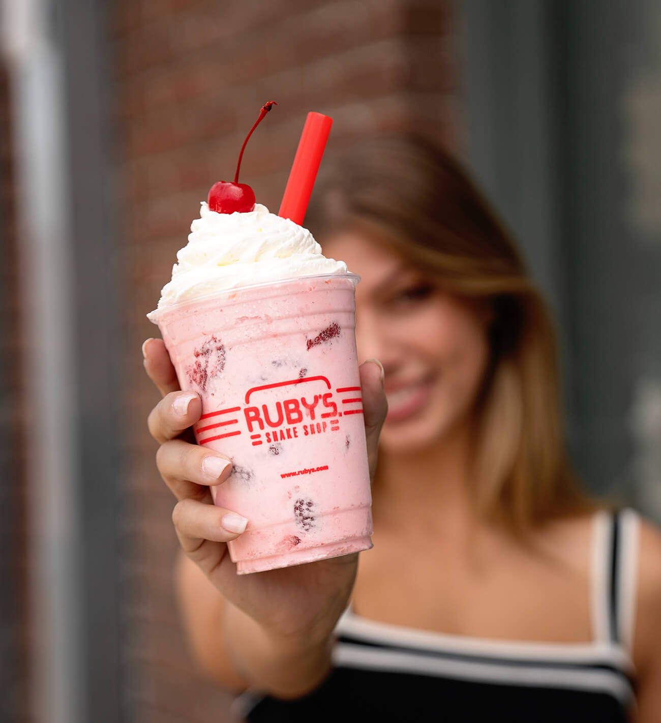 A woman holding a shake up close to the camera